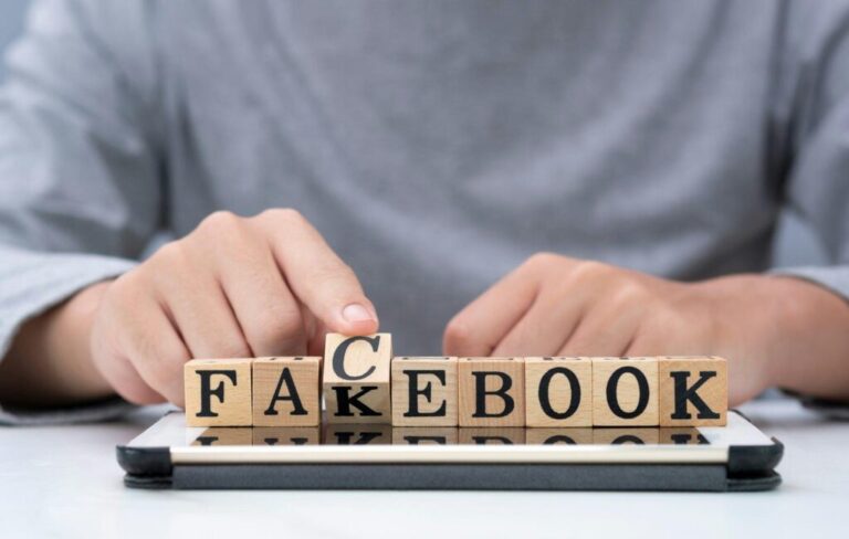 Hand flipping wooden woording for change "fakebook" to "facebook" on tablet