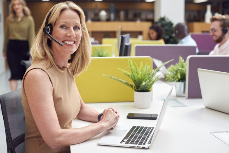 Portrait Of Mature Businesswoman Wearing Phone Headset Talking To Caller In Customer Services Centre