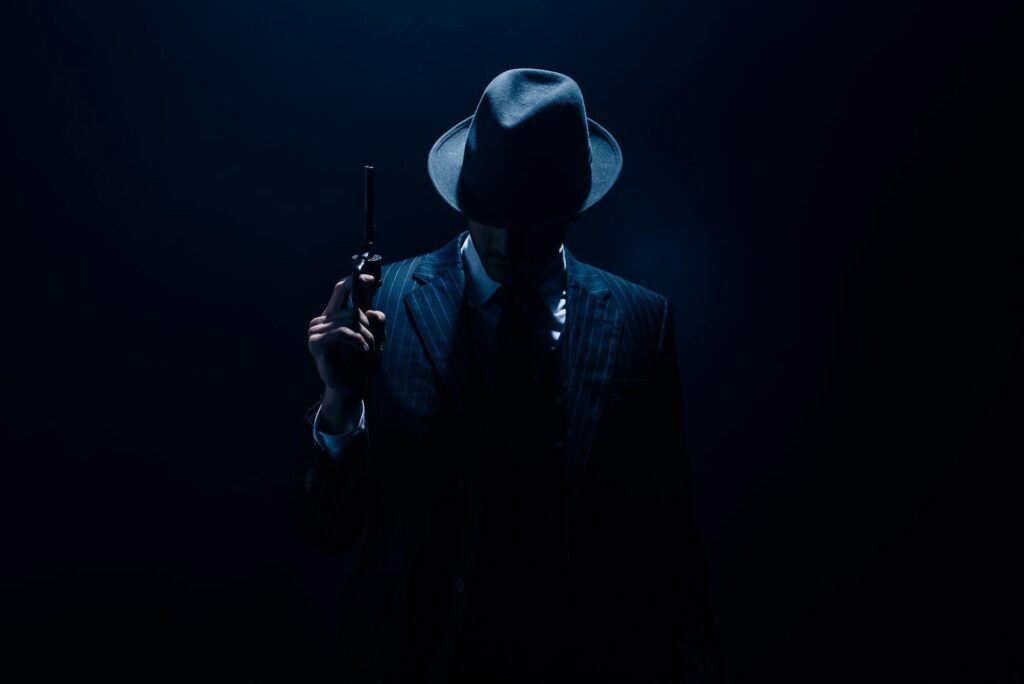 Silhouette of gangster raising gun on dark blue background