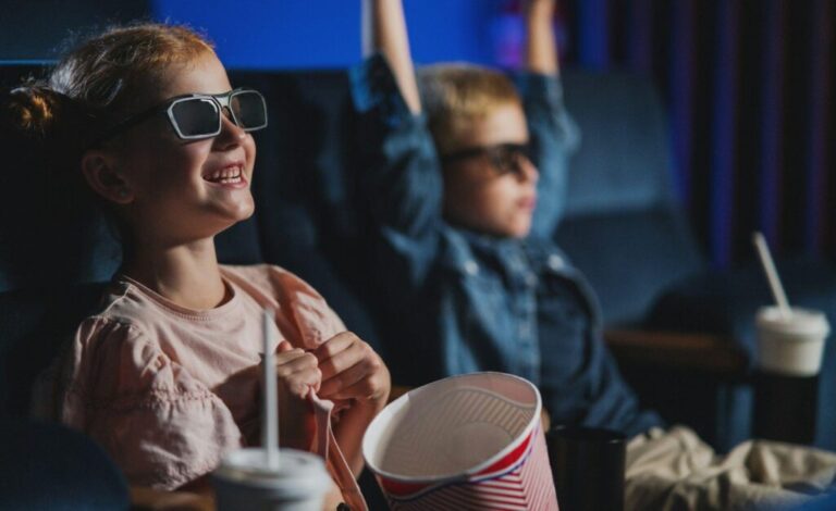 Small children with 3d glasses and popcorn in the cinema, watching film