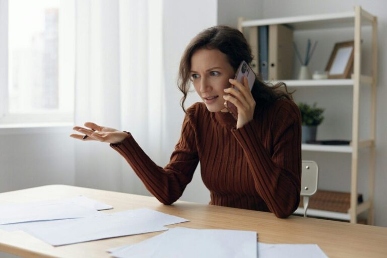 Fake debt notification. Confused angry irritated focused curly lady talk with frauds in call quarrel