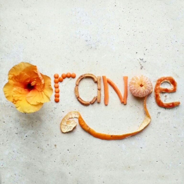 orange,creative typography made with food and flowers on stone table