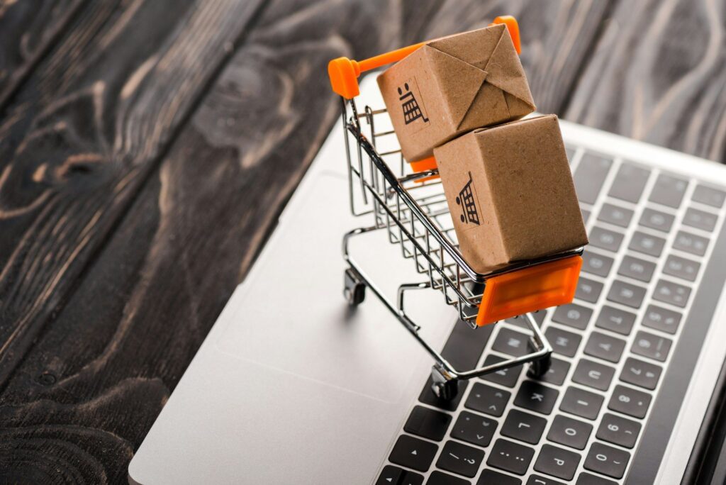 toy boxes in small shopping cart on laptop, e-commerce concept