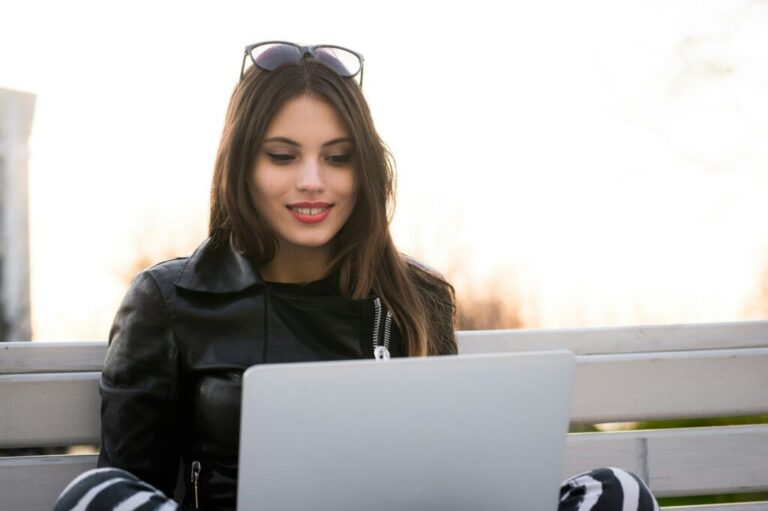 Close portrait of gorgeous dark-hair woman student using laptop computer at campus, charming female