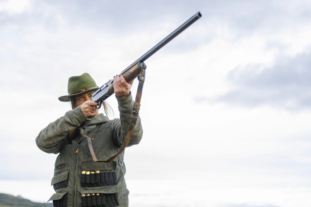 Hunter woman with shotgun hunting in the field.