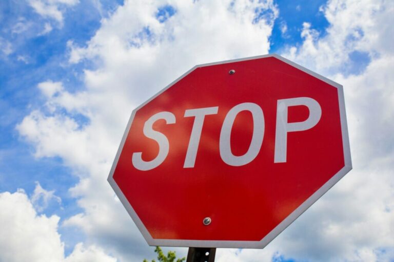 Red stop sign on the street, roadside traffic for stopping.