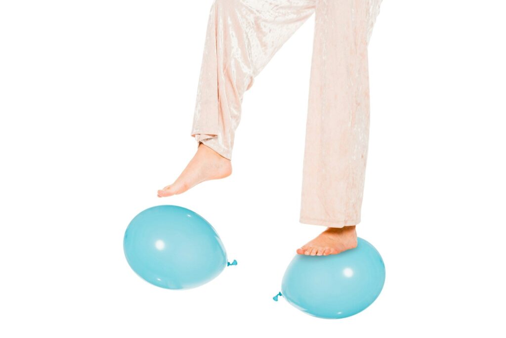 partial view of girl levitating in air and standing on blue ballons