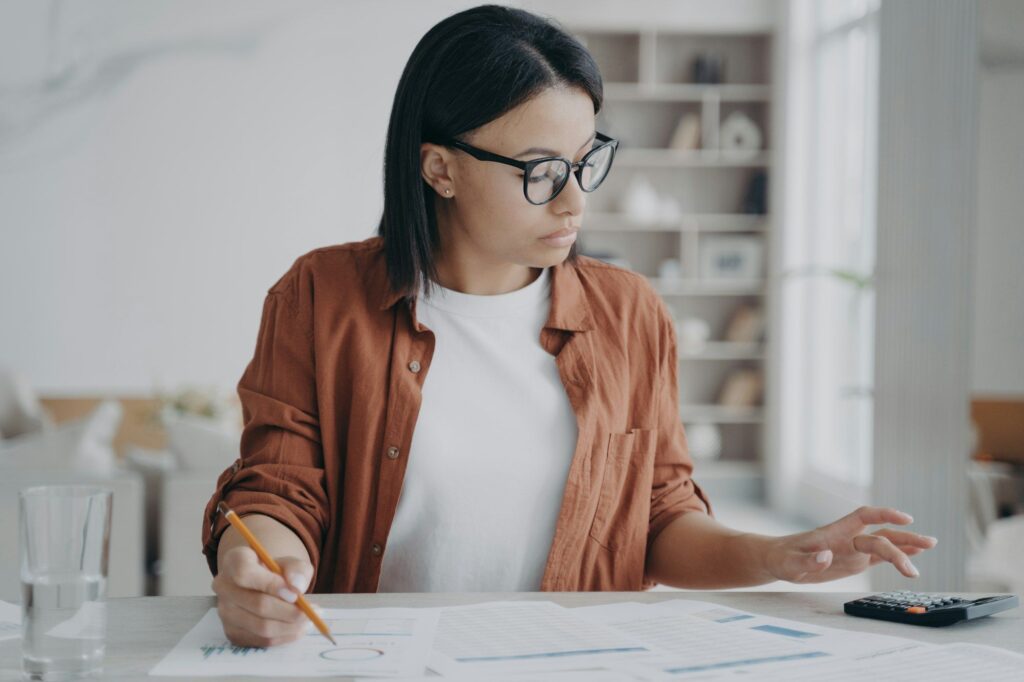 Businesswoman in glasses counts expenses on calculator, manages company budget. Financial management