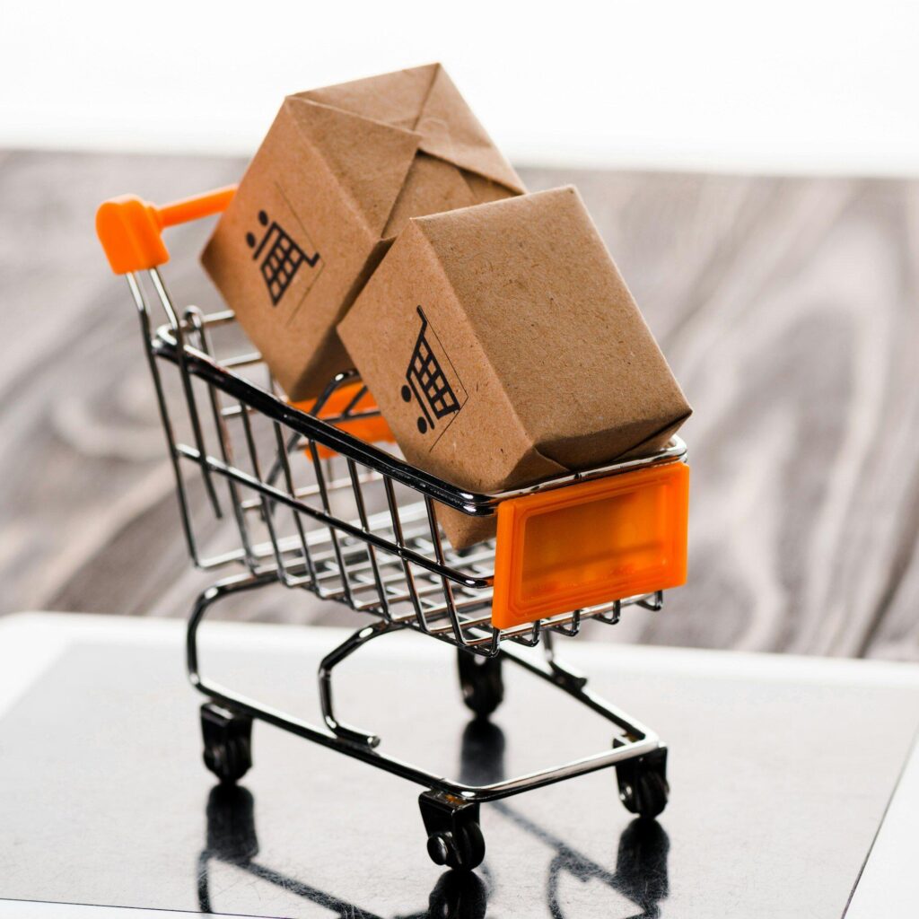 close up of toy shopping cart with small boxes on digital tablet, e-commerce concept