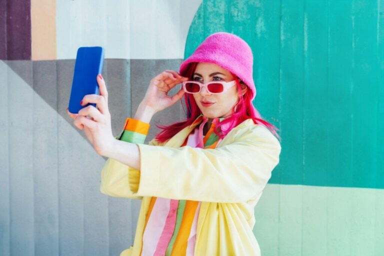 Emotional pink hair woman taking selfie photo on graffiti background.