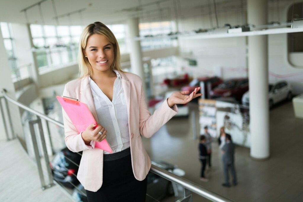 Professional salesperson selling cars at dealership to buyer