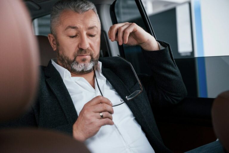 Sitting in the car and looking on the eyeglasses. Businessman is have free time