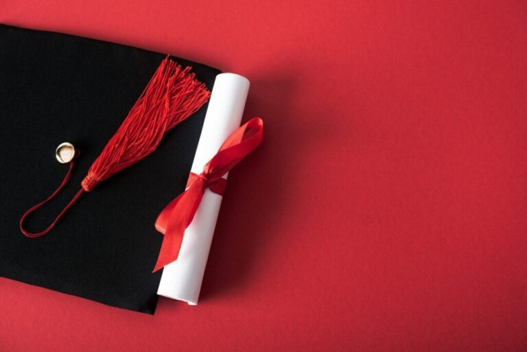 Top view of diploma with beautiful bow and graduation cap with tassel on red background