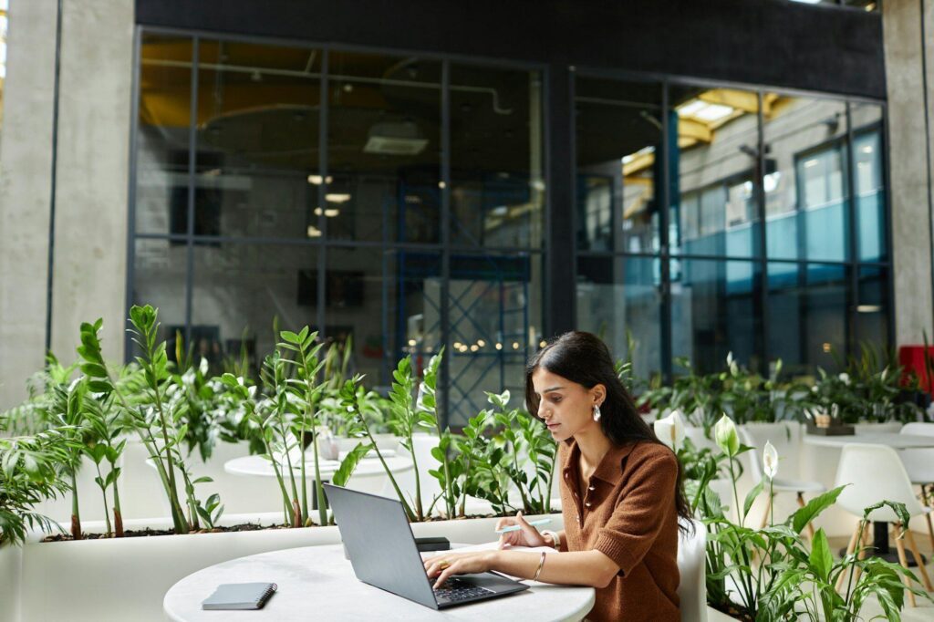 Woman Typing on Laptop Working on Business Plan at Cafe Table in Office Center