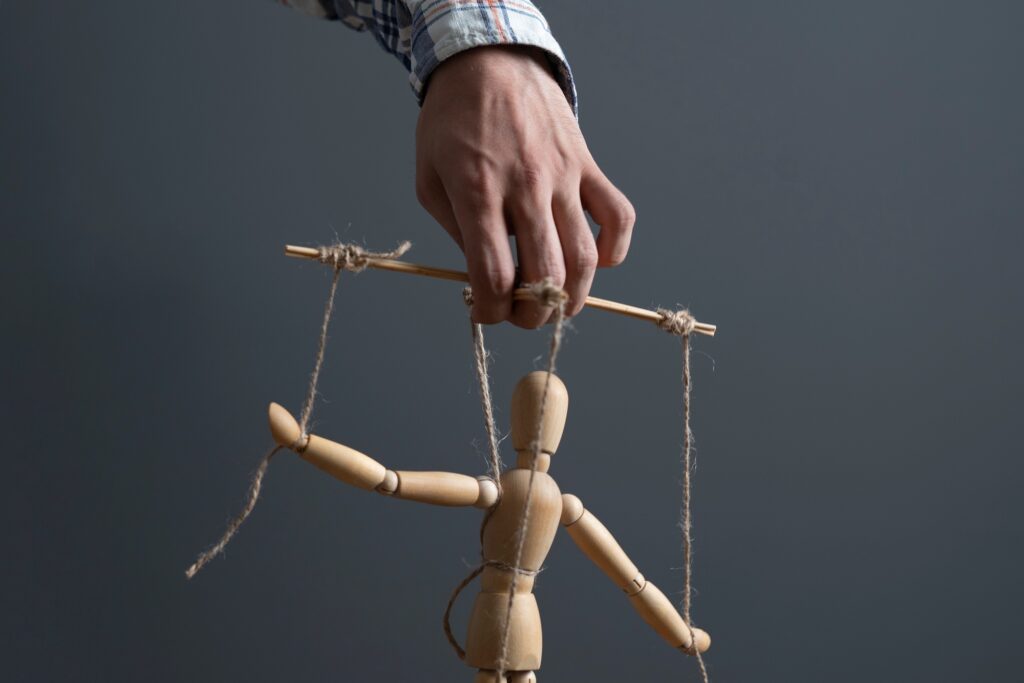 a hand manipulate threaded puppet marionette, human manager master