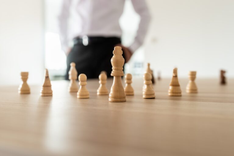 Chess pieces with king in the leading position placed on office desk