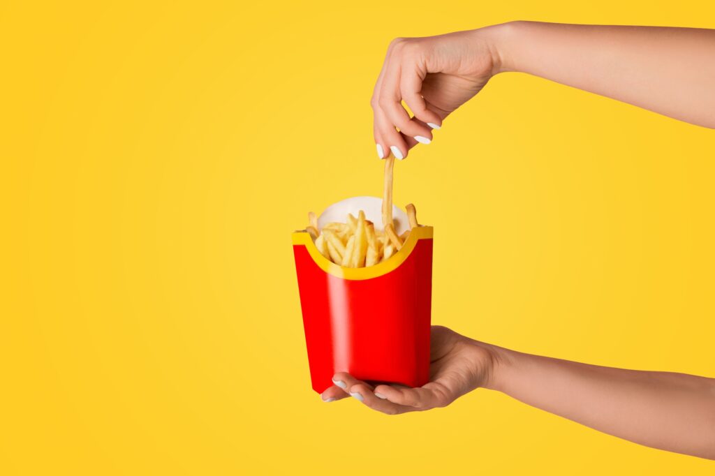 KHARKIV, UKRAINE - APRIL 4, 2020: Young girl holding pack of french fries from McDonald's on pink