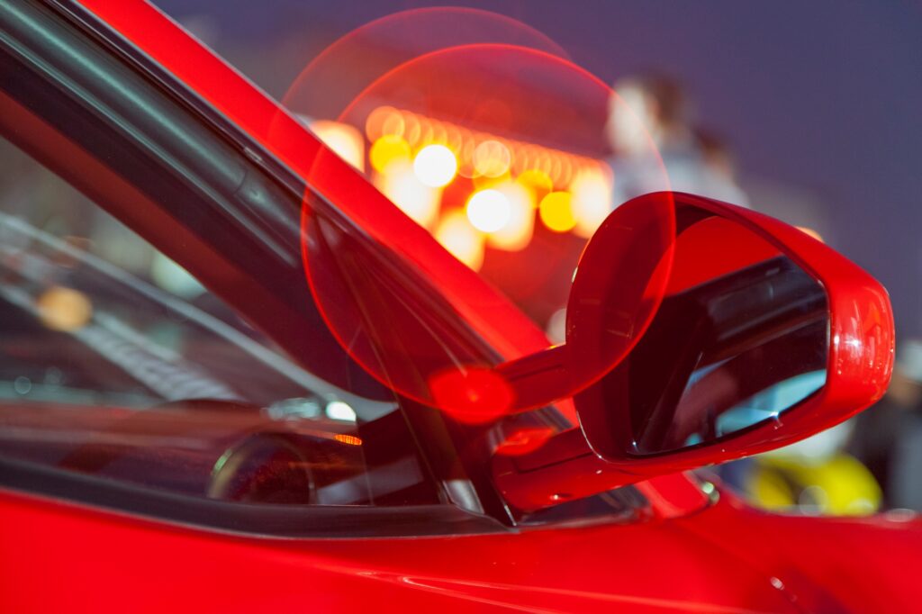 Luxury red car, closeup details with city lights behind it. Bokeh.