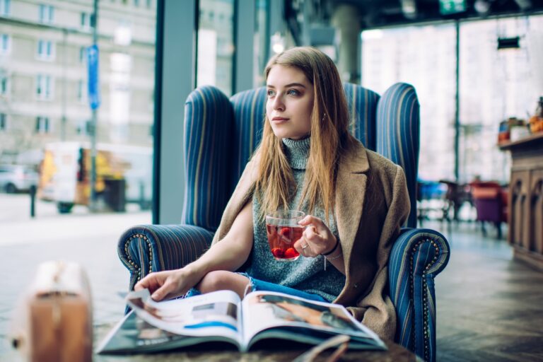 Pensive woman reading magazine in cafe