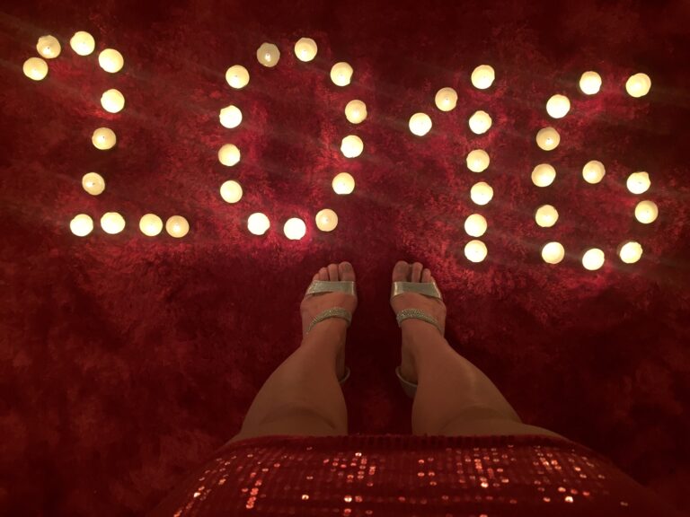 2016 sign on the carpet written with litten candles at a woman's feet