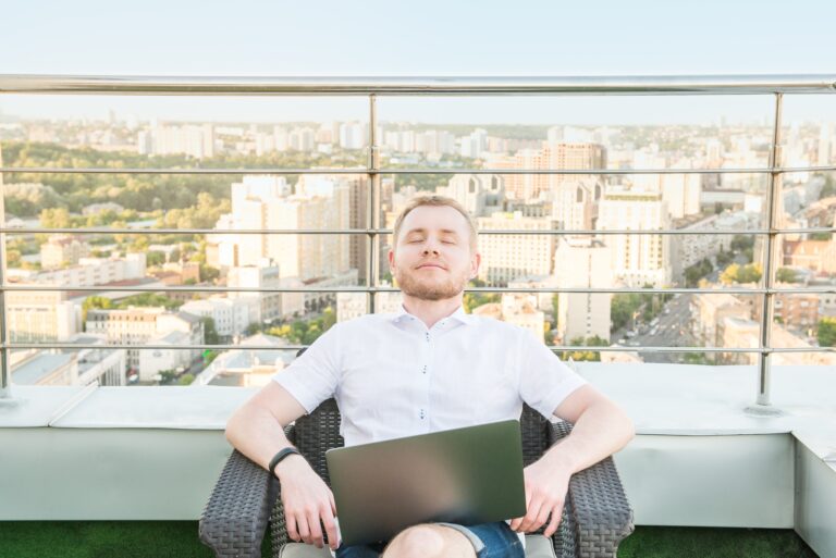 Satisfied and relaxed man with the laptop after well work done on an open terrace