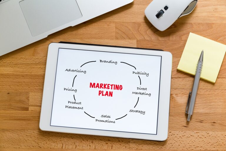 Modern working table with laptop computer with tablet showing marketing planning